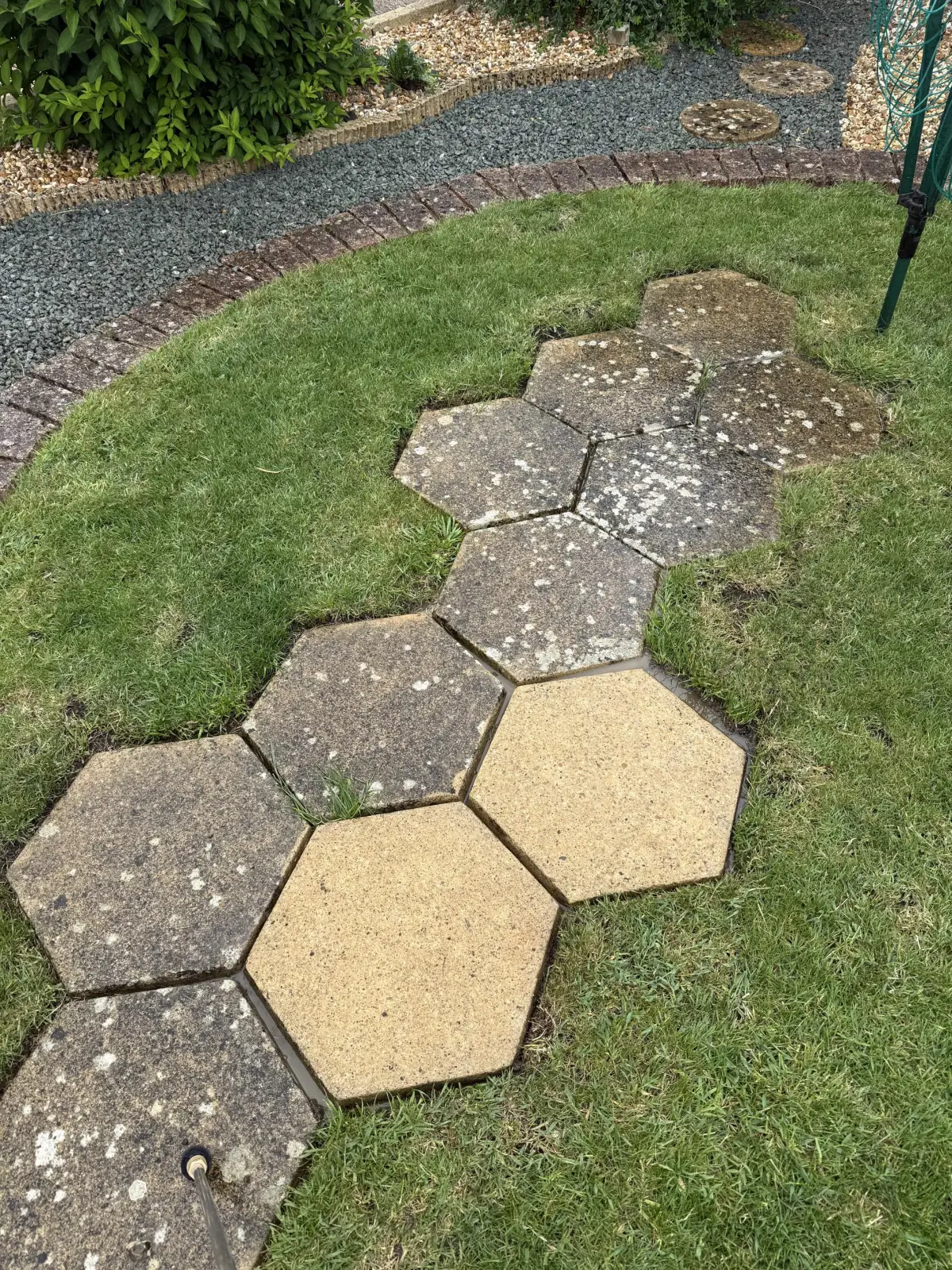 Part-cleaned garden paving showing the difference pressure washing can make