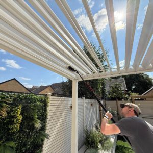 Window cleaner using a telescopic pole to clean a white conservatory roof
