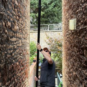 Window cleaner using a telescopic pole between stone walls