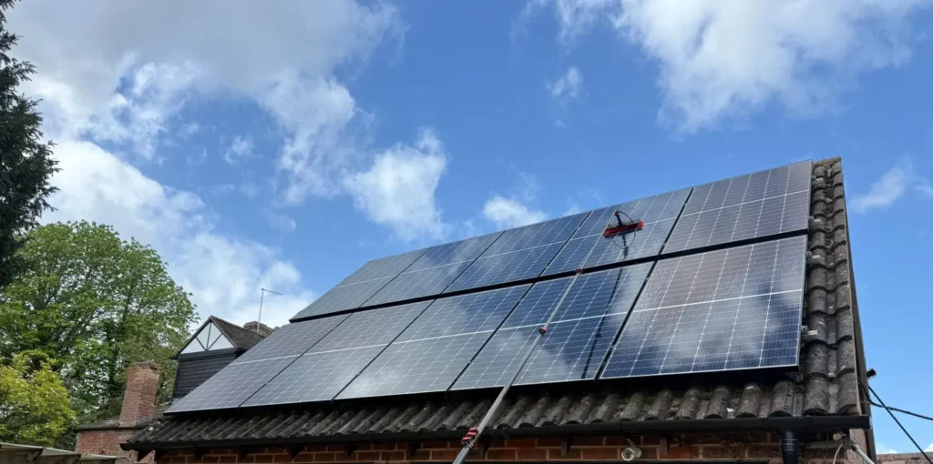 Solar panels being professionally cleaned with a soft water-fed brush from ground level