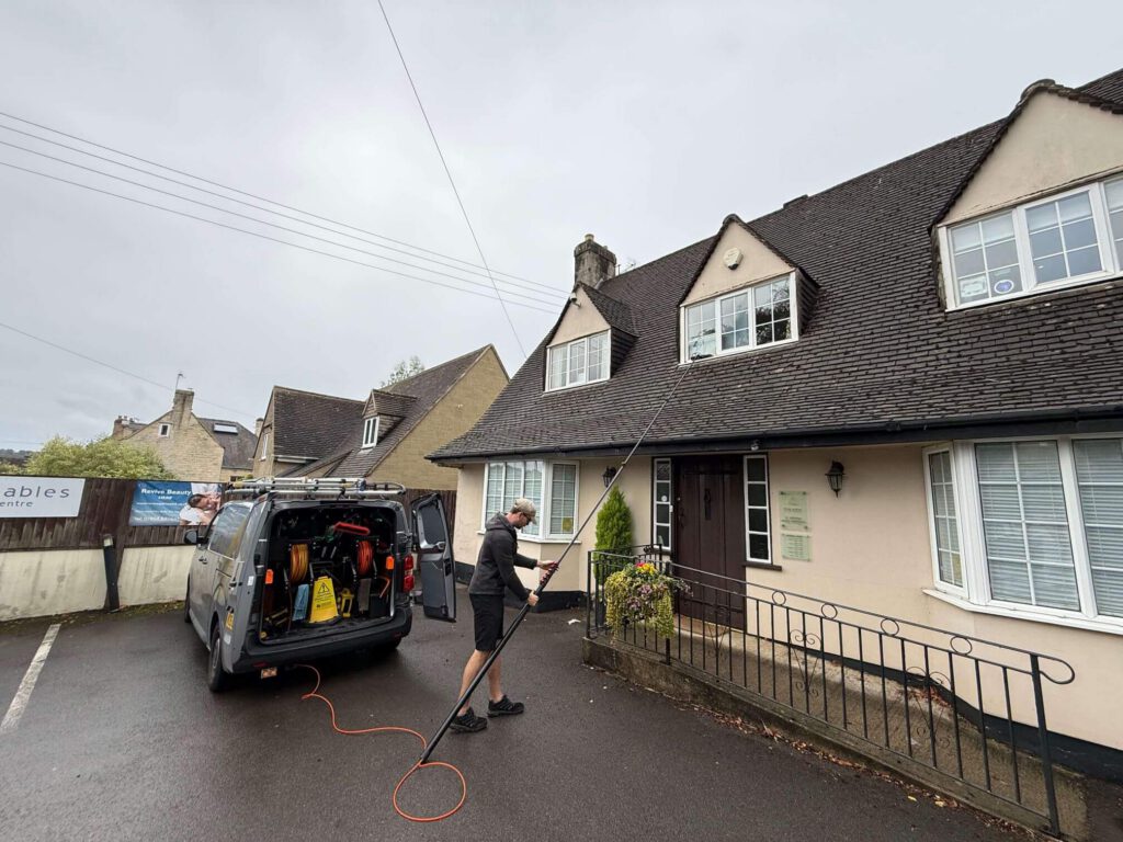 Crystal Clear Gloucestershire cleaning windows outside a private dental practice in Painswick, beside the cleaning van