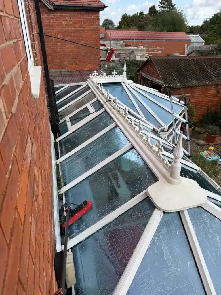 Cleaning brushes on the wet glass roof of a white conservatory beside the house on Finlay Road, Gloucester