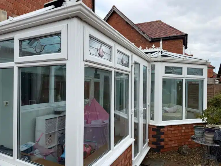 White conservatory frames, glazed doors and decorative upper windows following cleaning on Finlay Road, Gloucester
