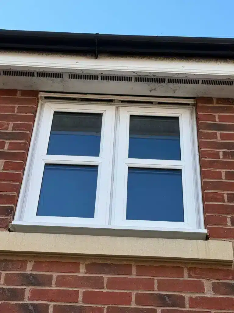 Build-up around the fascia and soffit above a window before cleaning in Uckington